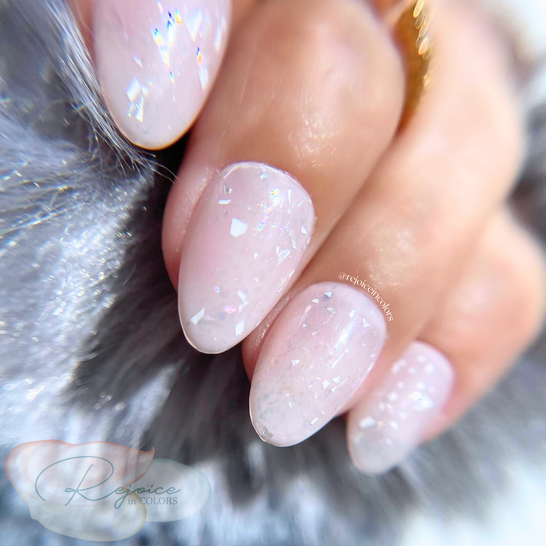 Nude base with broken flakes nail set on hand close up